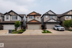 Contemporary two-story residence featuring a two-car garage, stone and siding facade, and a paved driveway - 