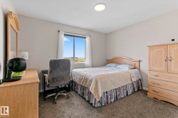 Bedroom featuring light neutral wall paint, carpet flooring, a window with white curtains, and a ceiling-mounted light fixture - 