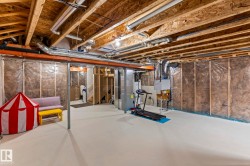 Unfinished basement space featuring exposed joists, ductwork, and fluorescent lighting - 