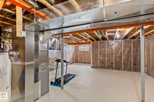 Unfinished basement offering expansive potential, featuring a painted concrete floor, visible ceiling joists, and insulated framed walls - 2131 51 Sw, Edmonton, AB - Indoor Photo Showing Basement