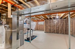 Unfinished basement offering expansive potential, featuring a painted concrete floor, visible ceiling joists, and insulated framed walls - 