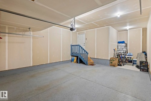 Spacious garage featuring a durable epoxy floor coating, interior access door, and a built-in staircase - 2131 51 Sw, Edmonton, AB - Indoor Photo Showing Garage