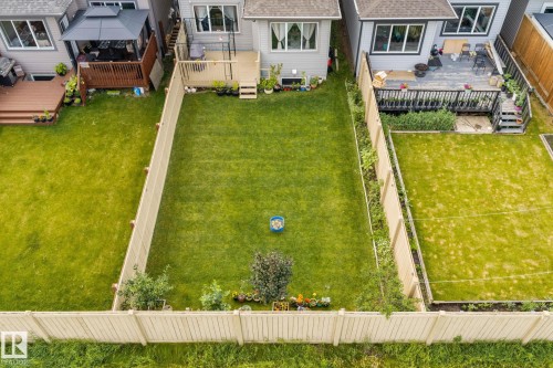 Expansive, fenced backyard featuring a large green lawn, mature plantings, and a private deck - 2131 51 Sw, Edmonton, AB - Outdoor