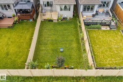 Expansive, fenced backyard featuring a large green lawn, mature plantings, and a private deck - 