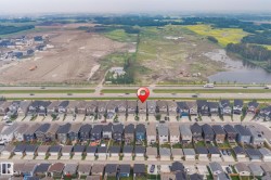 Aerial perspective of a developed residential street with rows of detached homes, featuring dark-toned roofs - 