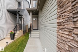Contemporary exterior with stacked stone accents, light-toned siding, and a covered entry - 