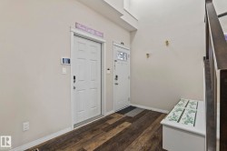 Entryway featuring wood-finish flooring, white trim, and a staircase with dark wood newel posts - 