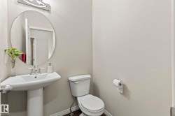 Pedestal sink featuring a chrome faucet, large circular mirror, and recessed lighting - 