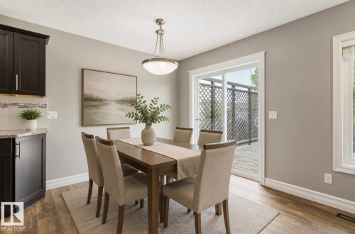 Dining area featuring wood-finish flooring, a contemporary pendant light fixture, and direct access to an outdoor deck via a sliding glass door - 79 Catalina Crest, Fort Saskatchewan, AB - Indoor Photo Showing Dining Room