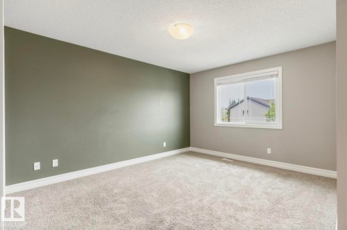 Spacious room featuring neutral carpeting, a large window, white trim, and a contemporary ceiling light fixture - 79 Catalina Crest, Fort Saskatchewan, AB - Indoor Photo Showing Other Room