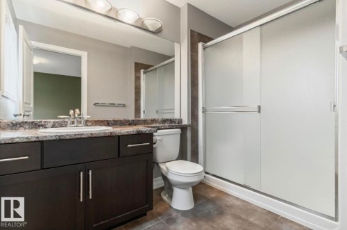 Full bathroom featuring a dark wood-finish vanity with a speckled countertop, an integrated sink, and a chrome faucet - 79 Catalina Crest, Fort Saskatchewan, AB - Indoor Photo Showing Bathroom