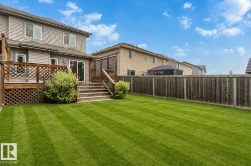 Expansive backyard featuring a manicured lawn with stripe patterning, a multi-level wooden deck with lattice detailing, and mature perimeter fencing - 79 Catalina Crest, Fort Saskatchewan, AB - Outdoor With Deck Patio Veranda