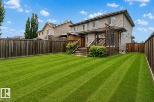 Expansive backyard featuring a manicured lawn, a full wooden fence, and a multi-level deck with lattice accents - 79 Catalina Crest, Fort Saskatchewan, AB - Outdoor