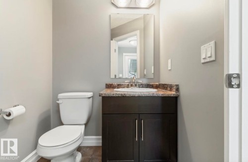 Bathroom featuring a dark wood vanity with a granite-look countertop, undermount sink, and chrome faucet - 79 Catalina Crest, Fort Saskatchewan, AB - Indoor Photo Showing Bathroom