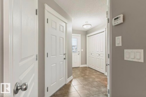Entryway featuring tile flooring, neutral wall tones, white trim, a semi-flush mount ceiling light, and panel doors - 79 Catalina Crest, Fort Saskatchewan, AB - Indoor Photo Showing Other Room