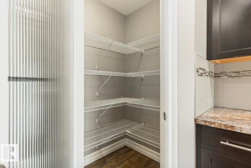 Corner pantry with multiple wire shelving units, wood-finish flooring, and white trim - 79 Catalina Crest, Fort Saskatchewan, AB - Indoor With Storage