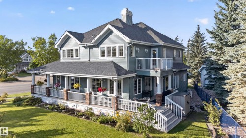Two-story exterior with light blue siding, a covered porch, multiple dormer windows, and a second-story balcony - 1251 Summerside Drive Sw, Edmonton, AB 