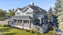 Two-story exterior with light blue siding, a covered porch, multiple dormer windows, and a second-story balcony - 