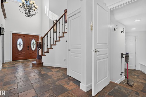 Foyer featuring a grand staircase with wrought iron balusters, double entry doors with decorative glass, and slate tile flooring - 1251 Summerside Drive Sw, Edmonton, AB 