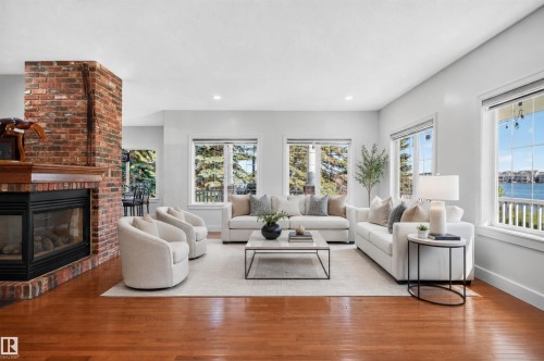 Hardwood flooring, a brick fireplace with a wood mantel, recessed lighting, and multiple windows with water scenery - 1251 Summerside Drive Sw, Edmonton, AB 