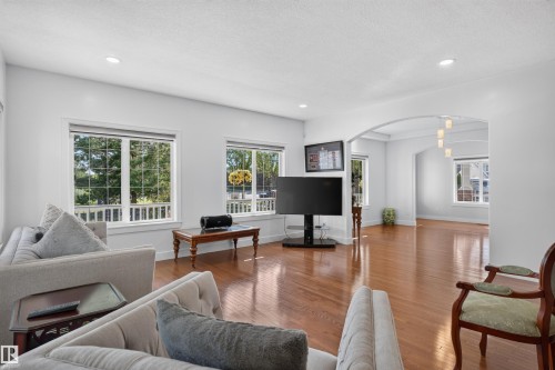 Hardwood flooring throughout, recessed ceiling lighting, multiple large windows, arched entryway, and a hanging light fixture - 1251 Summerside Drive Sw, Edmonton, AB 