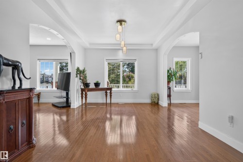 Hardwood flooring throughout, featuring arched doorways, coffered ceiling, and a multi-light pendant fixture - 1251 Summerside Drive Sw, Edmonton, AB 