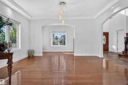 Wood-finish flooring throughout, arched entryway, tray ceiling with recessed lighting, pendant light fixture, and white trim - 