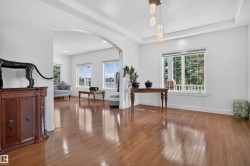 Hardwood flooring, recessed lighting, arched entryway, tray ceiling, and multiple windows - 