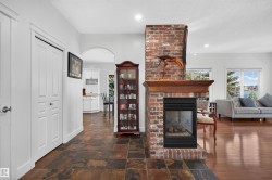 Brick-clad fireplace with wood mantel, tile flooring, wood-finish flooring, white paneled doors, and an arched doorway - 