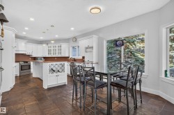 White cabinetry with crown molding, stainless steel appliances, a built-in wine rack, stone tile flooring, and multiple windows - 