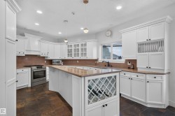 White cabinetry with crown molding, solid surface countertops, stainless steel appliances, built-in wine storage, and large format tile flooring - 