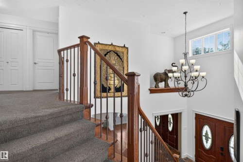 Staircase with wood banister and wrought iron spindles, carpeted treads, and white interior doors - 1251 Summerside Drive Sw, Edmonton, AB 