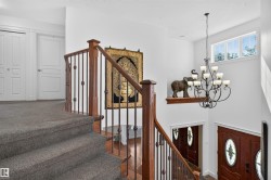 Staircase with wood banister and wrought iron spindles, carpeted treads, and white interior doors - 