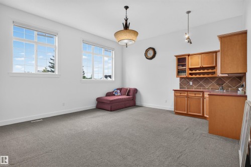 Recessed wet bar with wood cabinetry, integrated wine rack, and tile backsplash - 1251 Summerside Drive Sw, Edmonton, AB 