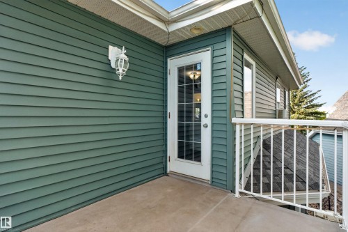 Exterior balcony with concrete flooring, white metal railing, and a glass-paned door - 1251 Summerside Drive Sw, Edmonton, AB 