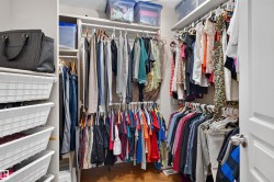 Walk-in closet with multiple hanging rods, built-in shelving, and wood-finish flooring - 