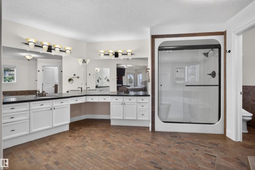 Dual vanity with dark countertops and white cabinetry - 1251 Summerside Drive Sw, Edmonton, AB 