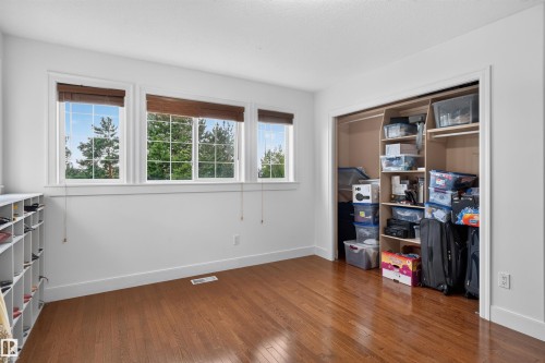 Wood-finish flooring, multiple windows with grid detailing, built-in closet storage, and integrated shelving - 1251 Summerside Drive Sw, Edmonton, AB 