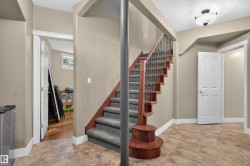 Wood-finish staircase with carpeted treads and decorative iron balusters - 