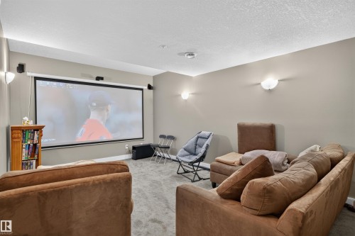 Media room featuring a large projection screen, wall-mounted sconces, and recessed lighting - 1251 Summerside Drive Sw, Edmonton, AB 