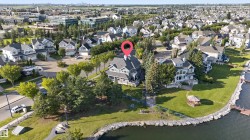 Lakeside property featuring a multi-story residence with a covered front porch, mature landscaping, and an adjacent gazebo - 