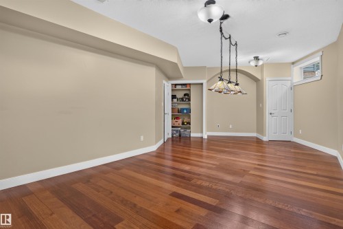 Expansive room featuring wood-finish flooring, recessed lighting, and a pendant light fixture - 1251 Summerside Drive Sw, Edmonton, AB 