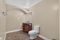 Arched wall detail with a round vanity and a clear vessel sink, complemented by a large wall-mounted mirror, mosaic-style flooring, and a contemporary toilet - 