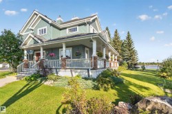 Two-story home with a wide covered front porch, white railings, and brick-clad columns - 