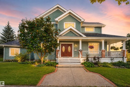 Two-story residence featuring a covered front porch, dual front entry doors, a concrete walkway, and a landscaped front yard with mature trees - 1251 Summerside Drive Sw, Edmonton, AB 