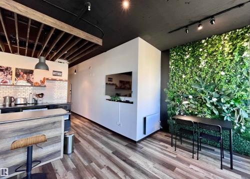 Wood-finish flooring throughout, exposed wood beam ceiling, contemporary track lighting, and a full-height decorative plant wall - #1701 10024 Jasper Av Nw, Edmonton, AB 