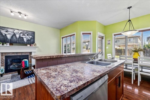 Kitchen island with a double basin sink, dark wood-finish cabinetry, and a built-in dishwasher - 11506 17 Avenue Sw, Edmonton, AB 