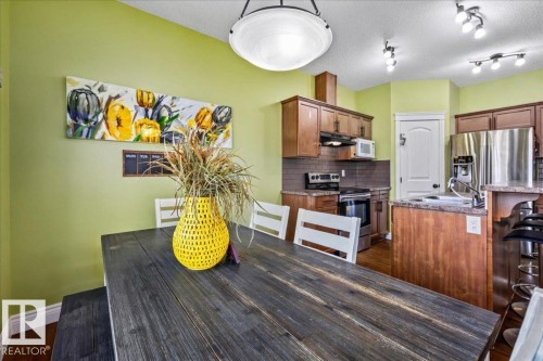 Wood-finish flooring, recessed lighting, wood cabinetry, stainless steel appliances, and a kitchen island with a sink - 11506 17 Avenue Sw, Edmonton, AB 