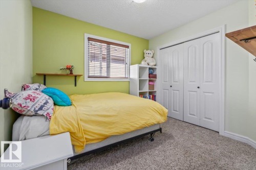 Carpeted flooring with light-toned wall paint and a built-in closet featuring bi-fold doors - 11506 17 Avenue Sw, Edmonton, AB 