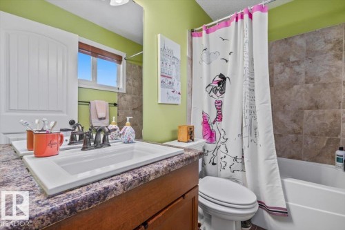 Bathroom featuring a built-in vanity with a drop-in sink, dark wood-finish cabinetry, and a stone-look countertop - 11506 17 Avenue Sw, Edmonton, AB 